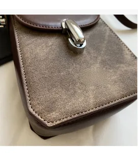 Detailed close-up of retro mini crossbody bag with leather stitching and metal buckle