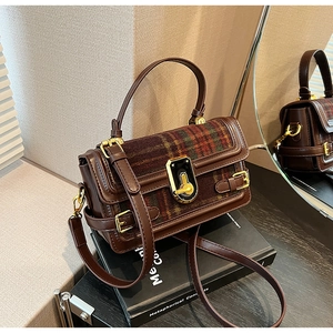 Detail of vintage brown plaid handbag featuring a gold turn-lock and leather texture