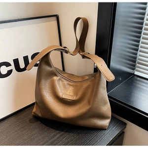 Détail de la texture en cuir marron rétro et de la bandoulière large du grand sac hobo