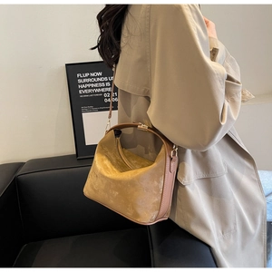 Détail d'un sac seau en daim kaki avec des finitions dorées et une fine bandoulière