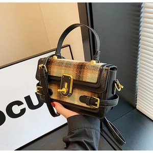 Detail of checkered crossbody bag with golden twist lock and black leather handle