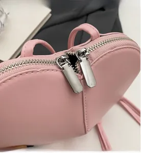 Dettaglio delle cerniere in metallo argentato su una borsa rosa a forma di cuore