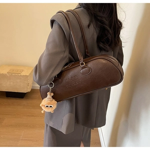 Detail of vintage dark brown barrel shoulder bag with brand embossing and plush pendant