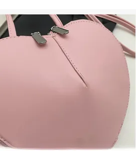 Dettaglio della borsa rosa a cuore con trama in pelle PU e doppia cerniera argentata