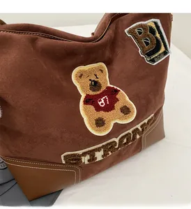 Detail of vintage brown tote bag with teddy bear patch and embroidered strong text