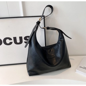 Détail d'un sac cabas vintage en cuir noir avec ferrures dorées et logo embossé