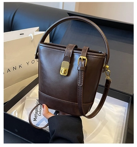 Detail of vintage dark brown leather bucket bag with gold hardware in gift packaging