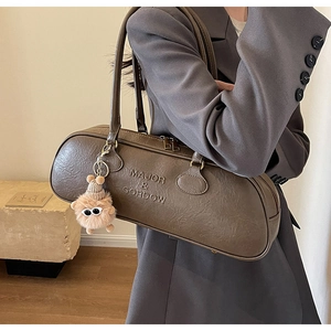 Detail of dark brown leather shoulder bag with plush monster charm and embossed logo