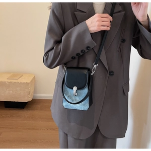 Detail view of denim and leather crossbody phone bag on model showing size and fit