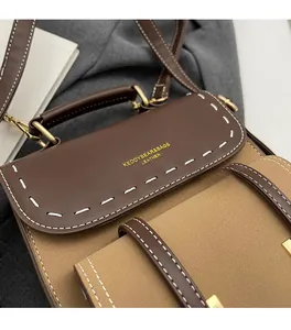 Detail of two-tone leather bag with contrast stitching and gold logo lettering