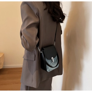 Detail view of retro crossbody phone bag in blue denim and black leather worn by model