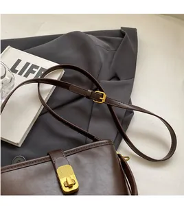 Detail view of the brown leather shoulder bag featuring adjustable gold metal buckle on strap