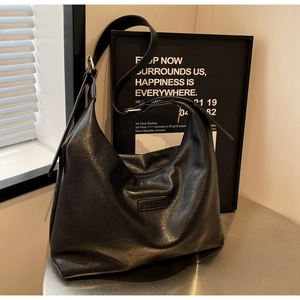 Détail de la texture en similicuir noir mat et logo embossé sur le grand sac cabas hobo