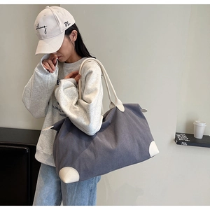Dettaglio della borsa tote in velluto a coste grigio-blu con manici in pelle bianca