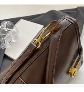 Detail of dark brown leather handbag featuring gold metal hardware and stitching