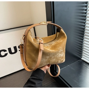 Détail de la texture en daim jaune moutarde et des bretelles en cuir marron du sac à main