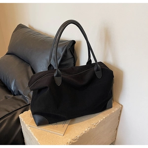 Dettaglio della borsa tote in velluto nero con manici in pelle e trama materica