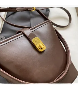 Close-up of vintage brown leather bucket bag with textured golden metal lock detail