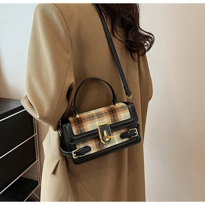 Detail of tweed and black leather crossbody bag with elegant golden clasp and adjustable strap