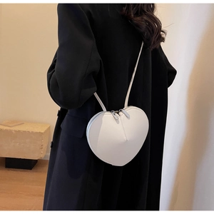 Vista dettagliata di una borsa a tracolla in pelle bianca a forma di cuore su un cappotto