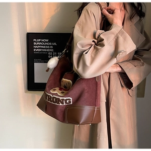 Detail of vintage brown canvas tote bag with teddy bear embroidery and strong letter decor