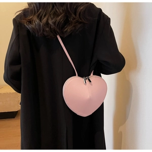 Dettaglio ravvicinato di una borsa a tracolla rosa a forma di cuore su un cappotto nero