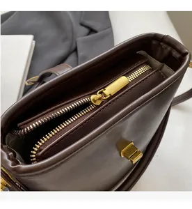 Detail showing smooth gold metal zipper and textured brown faux leather of the bucket bag