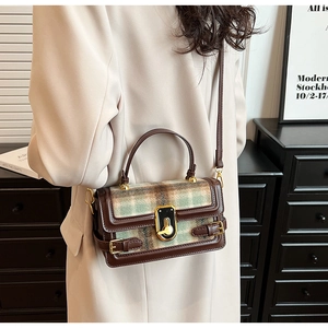 Detail of vintage plaid crossbody bag with brown leather trim and golden buckle