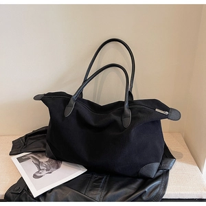 Dettaglio della borsa tote in velluto a coste nero con trama del tessuto e rinforzi in pelle