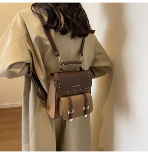 Rear view of a model carrying a vintage brown two-tone backpack with top handle and stitching