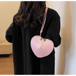 Borsa a tracolla rosa a forma di cuore in ecopelle indossata su un cappotto nero elegante