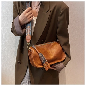 Detailopname van een bruine vintage lederen crossbodytas met een brede geweven riem
