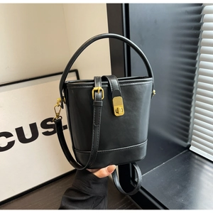 Close-up of black leather bucket bag featuring a golden twist lock and top handle