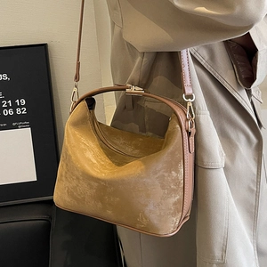 Sac à bandoulière rétro marron en daim mat avec fermoir doré sur manteau beige