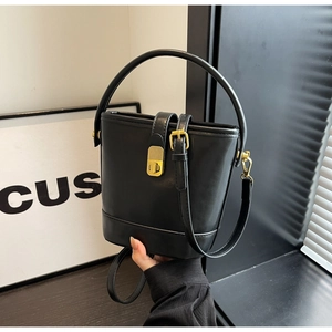 Detail view of the black leather bucket bag with golden metal clasp and carry handle