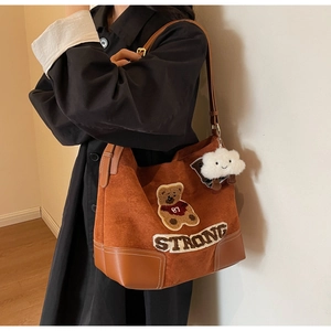 Detail of brown suede tote bag with teddy bear embroidery and fluffy cloud charm