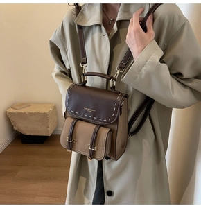 Close-up of retro backpack with brown flap and contrast stitching worn by a model