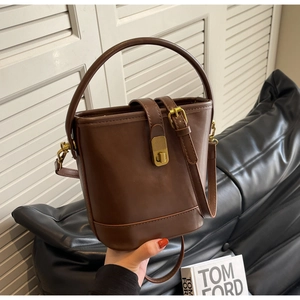 Close-up of vintage brown bucket bag with golden turn-lock closure and leather handle