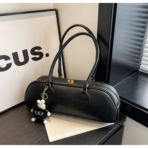 Detail of black leather Boston bag with brand engraving and fuzzy monster charm