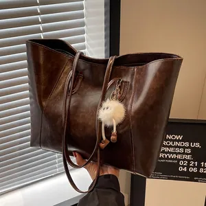 Retro brown faux leather tote bag with long straps and cute white plush monster charm