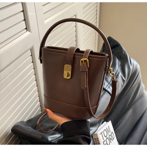 Detail view of a vintage brown leather bucket bag with elegant golden turn-lock closure