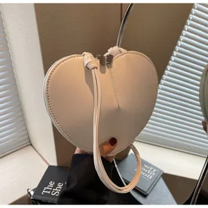 Dettaglio della borsa a forma di cuore bianca con cuciture fini e doppia cerniera in metallo