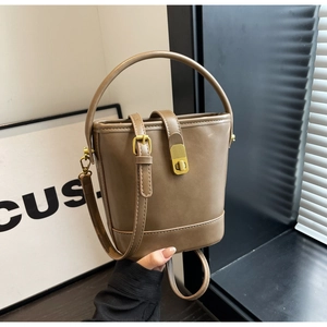 Close-up of vintage brown bucket bag featuring gold metal clasp and top handle