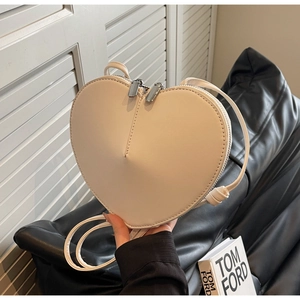Dettaglio della borsa a tracolla crema a forma di cuore con cerniere in metallo