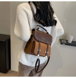Detail of vintage brown leather backpack with contrast stitching and double buckle pocket