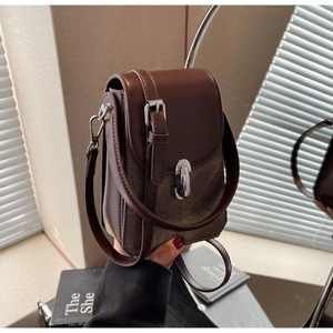 Close-up of vintage crossbody phone bag featuring two-tone leather and canvas with metal lock