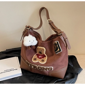 Detail of vintage brown suede tote bag with embroidered bear patch and cloud charm
