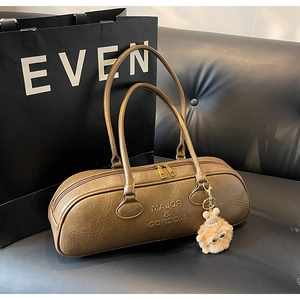 Detail of vintage brown cylinder Boston bag with logo and cute plush charm on sofa