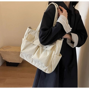 Detail view of cream corduroy tote bag with two front pockets shown on model