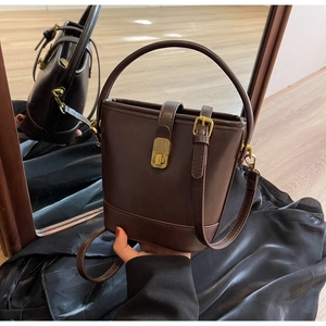 Detail view of a vintage dark brown leather bucket bag with elegant gold hardware buckles